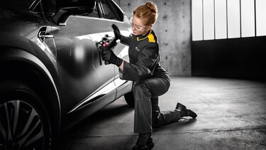 Mitarbeiterin mit Handschuhen untersucht Renault Wagen 